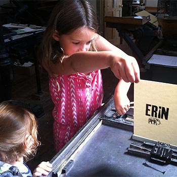 Justin & Cecilia’s eldest daughter Freya printing wood type on a proofing press